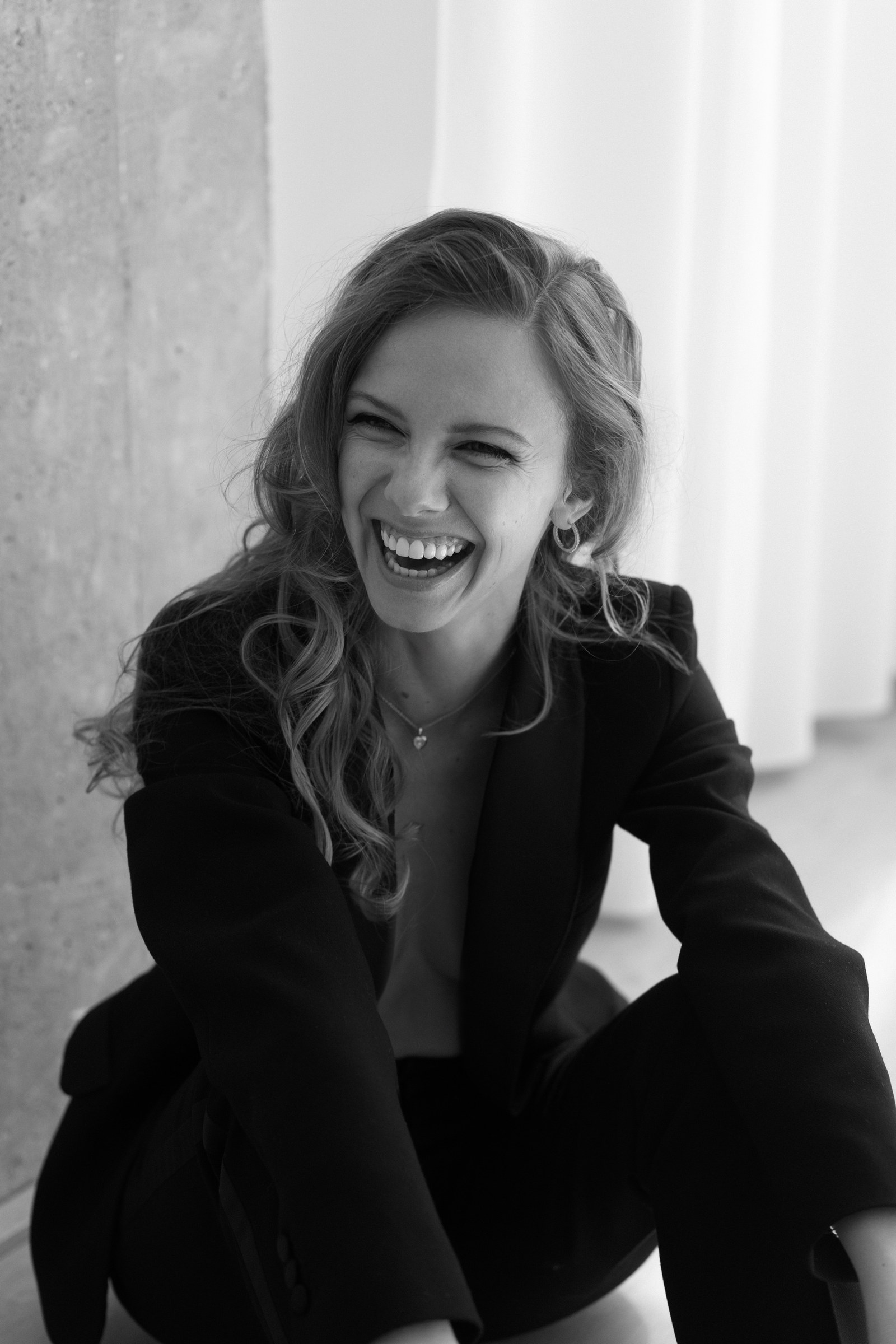 Black and white photo of Nata in her black suit, laughing